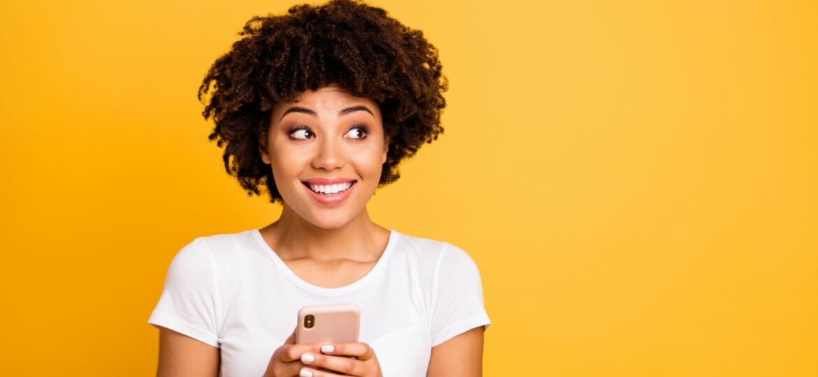 Portrait of her she nice cute attractive lovely charming cheerful cheery wavy-haired lady holding in hands cell looking aside isolated on bright vivid shine yellow background